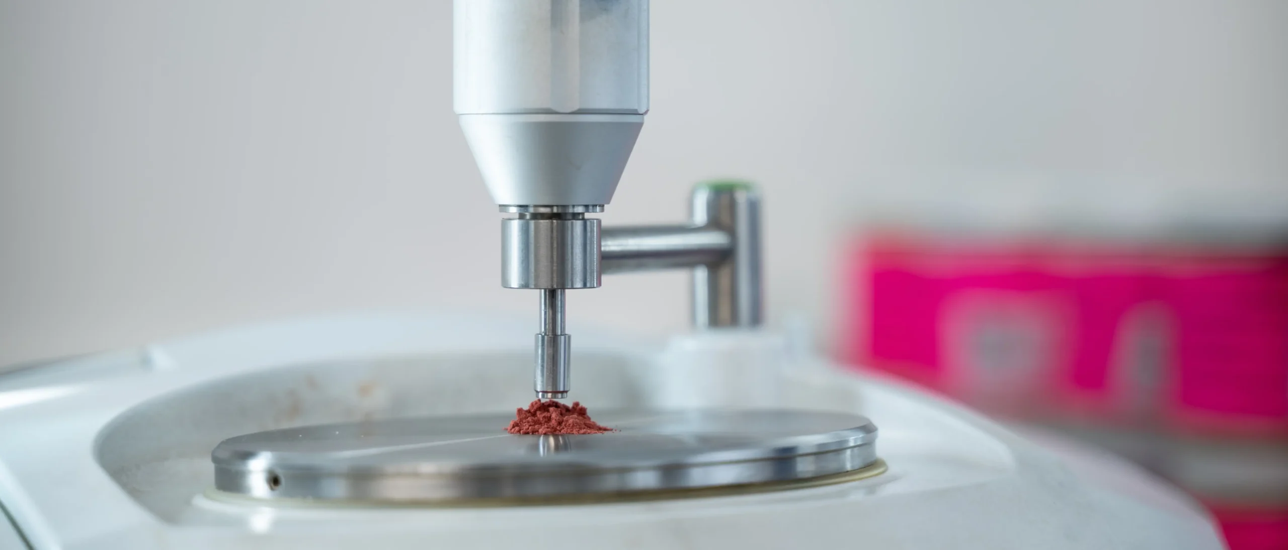 Advanced laboratory testing equipment measuring a small powder sample on a metal testing platform, used for material analysis and quality testing.